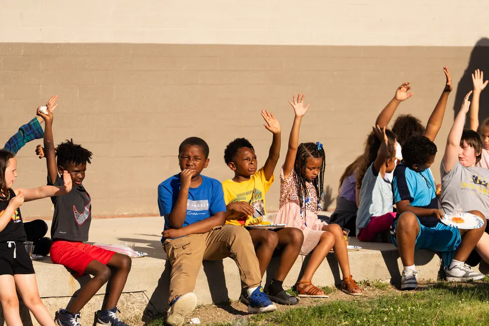 Kids raising their hands and smiling